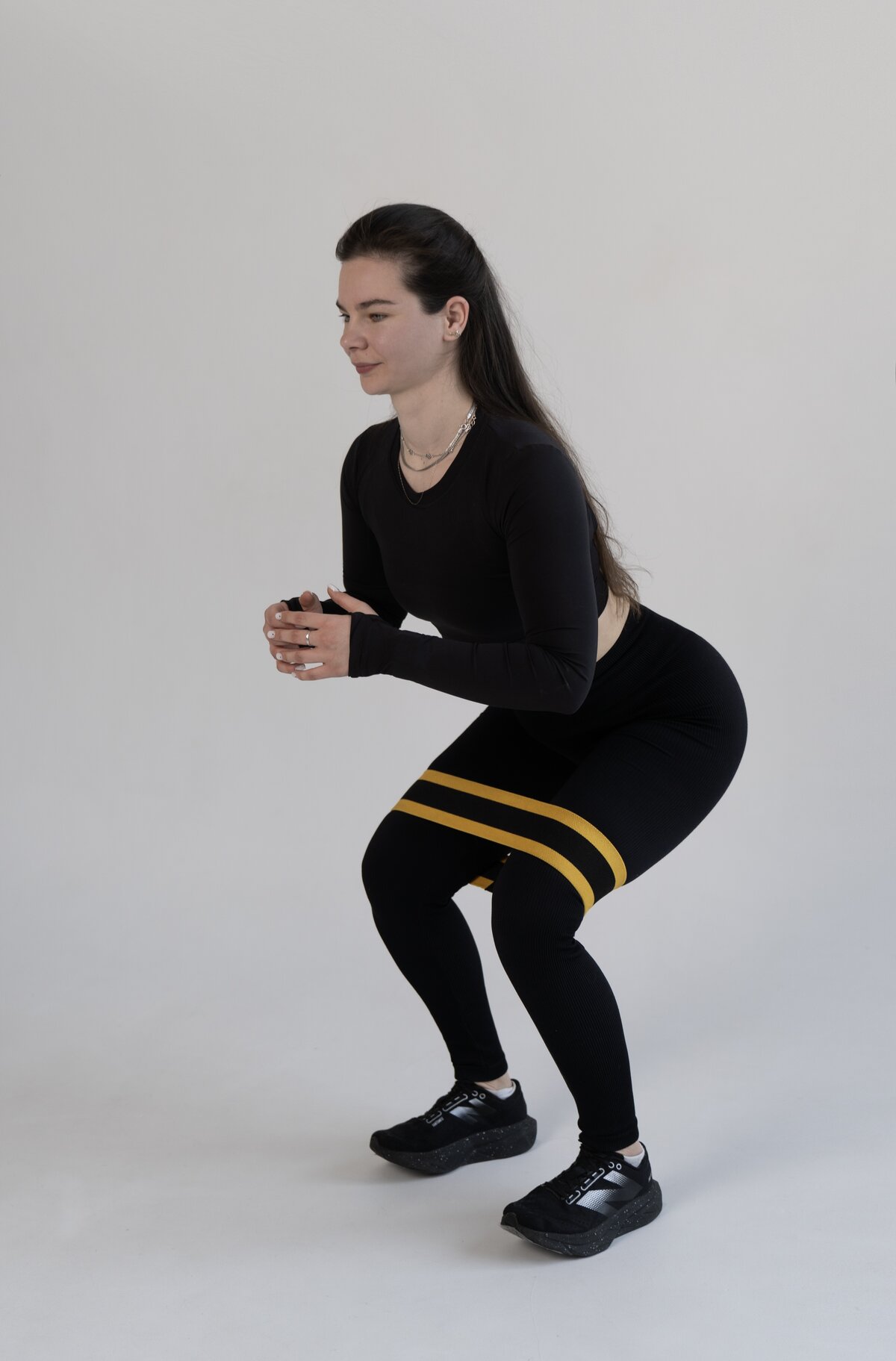 Olena Hilova demonstrating a resistance-band squat, an exercise she coaches in live online sessions